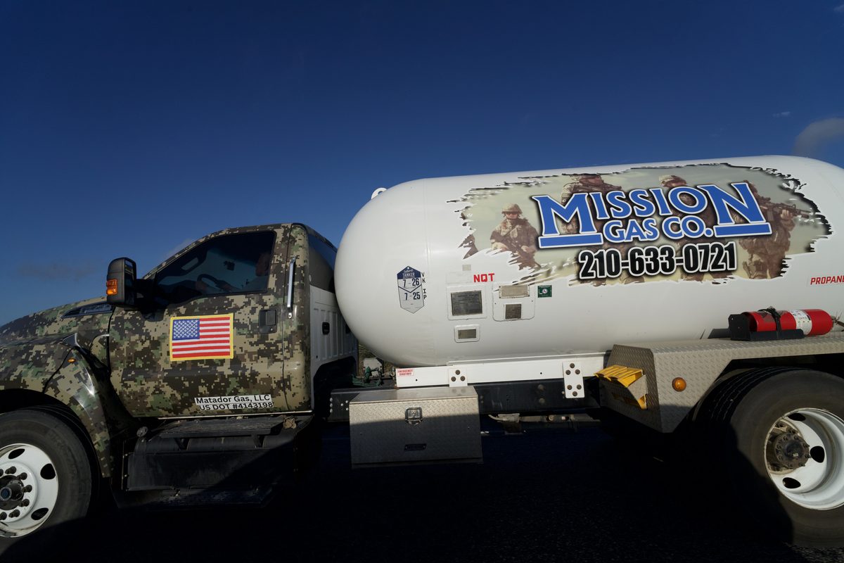 Camouflage-wrapped propane truck with a white tanker trailer branded Mission Gas Co. and a phone number