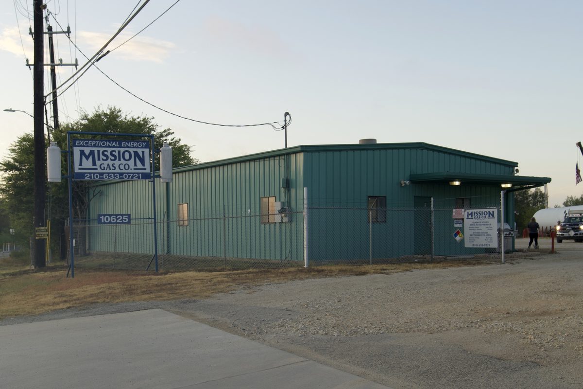 Mission Gas Co. building with sign and trucks parked outside at dusk