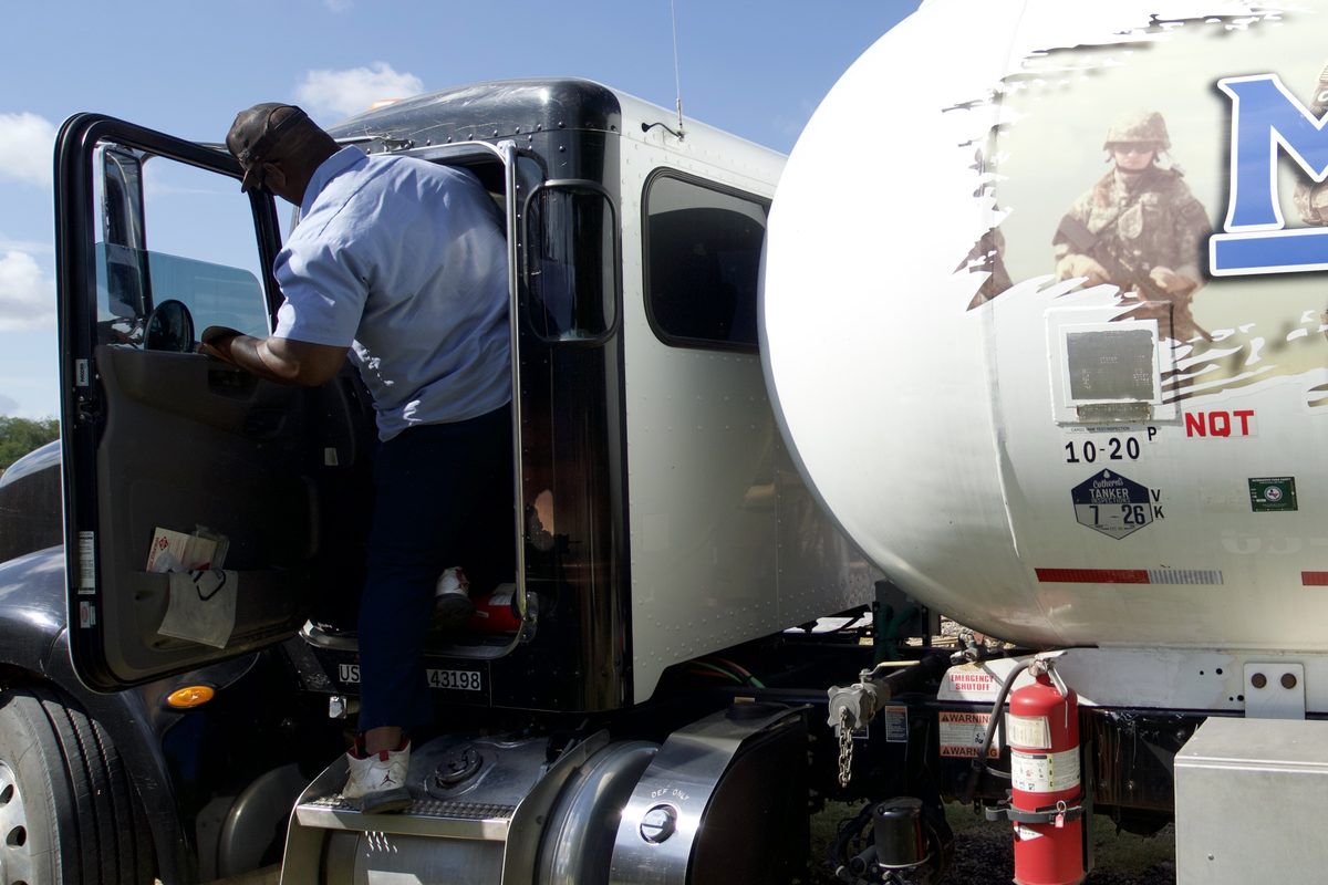 Mission Gas Co. propane tanker truck with military-themed graphics as a driver enters the cab