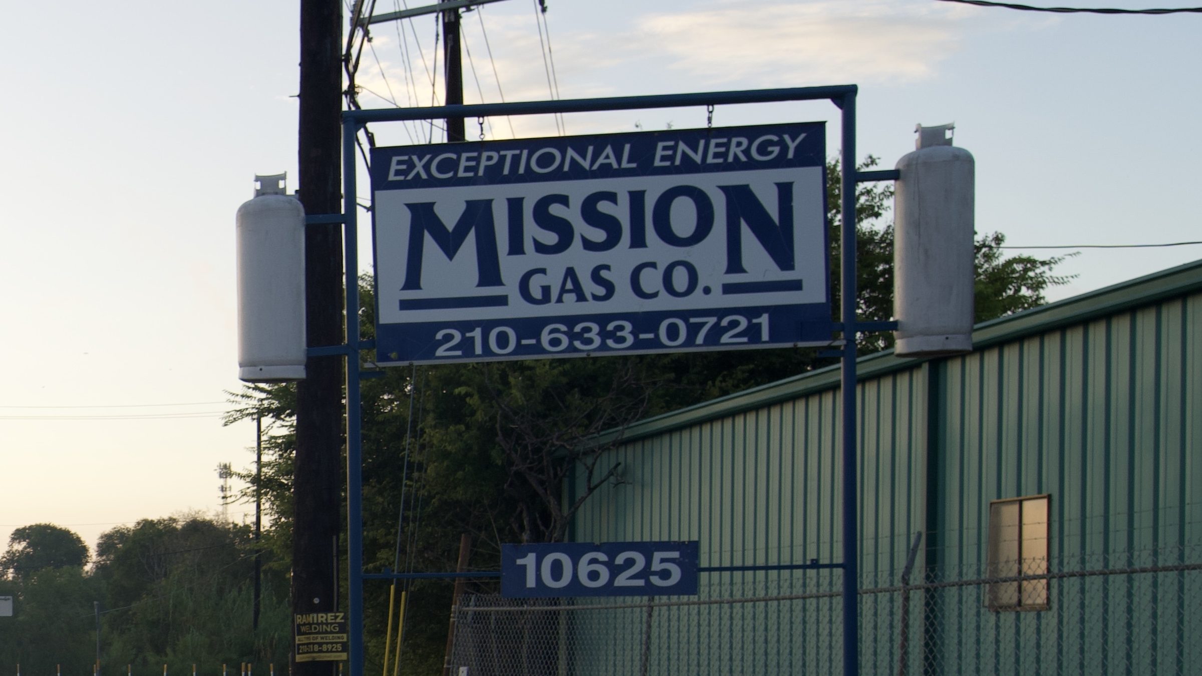 Mission Gas Co. sign with propane tanks along a road at dusk in San Antonio