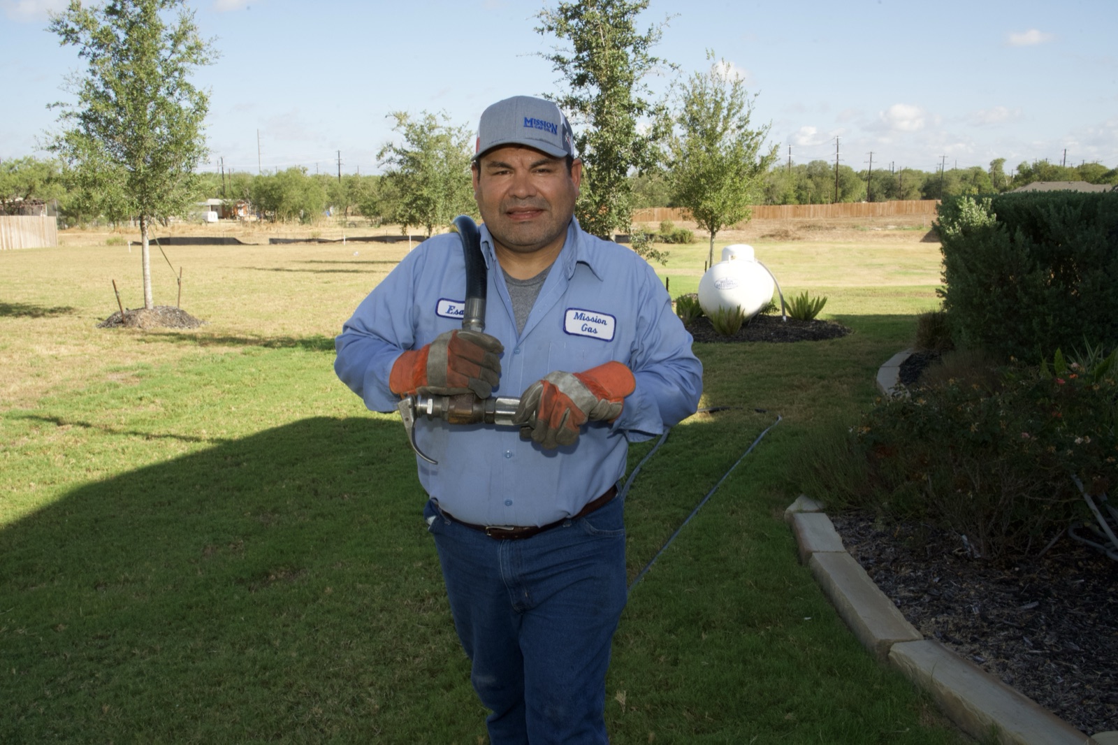Staples, TX technician performing propane tank refill service in a residential yard