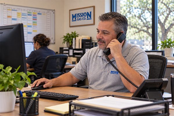 Mission Gas office staff member taking a customer phone call at his desk